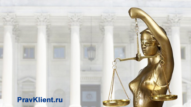 Золотая статуэтка Фемиды стоит на фоне здания с колоннами