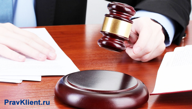 Судья держит в руке деревянный молоточек