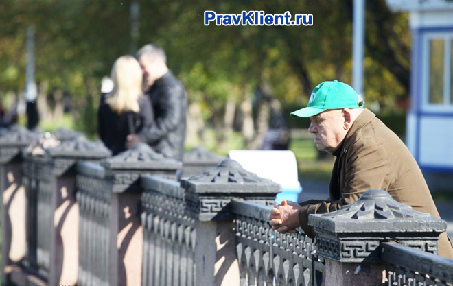 Одинокий пенсионер стоит на мосту