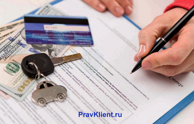 Мужчина расписывается в документах, рядом лежат банковская карточка и ключи с брелком в виде машинки