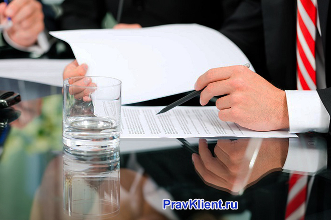 Бизнесмен подписывает документацию за зеркальным столом