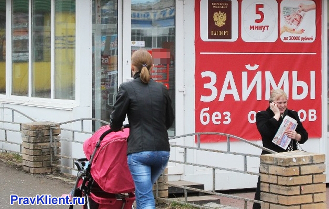 Девушка гуляет с коляской мимо рекламы микрозаймов