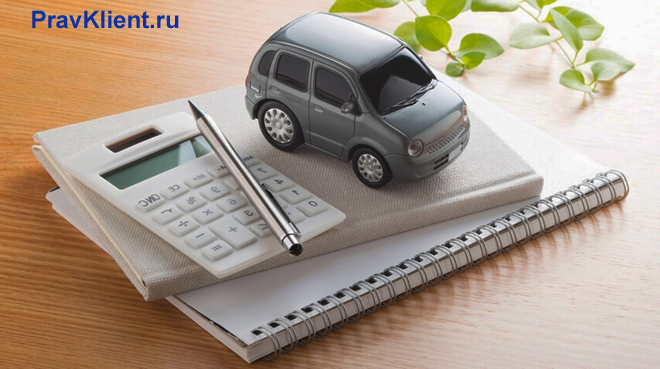 Машинка стоит на тетради, рядом лежит калькулятор