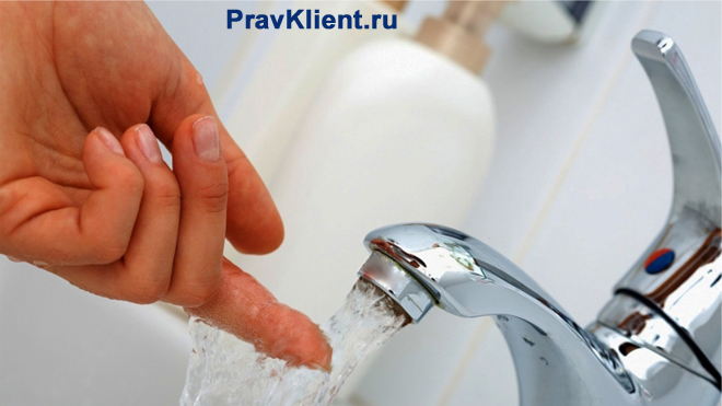 Человек трогает рукой струйку воды из-под крана