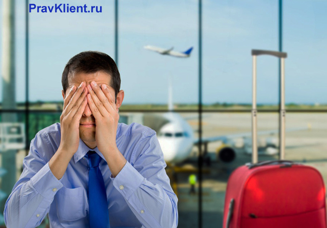 Уставший мужчина сидит в аэропорту