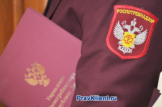 Сотрудник Роспотребнадзора держит в руке папку с документами