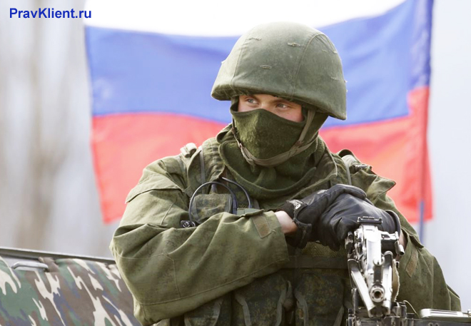 Военный в экипировке на фоне флага РФ