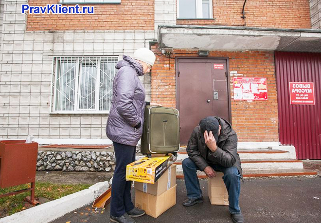 Семейная пара около подъезда в чемоданами