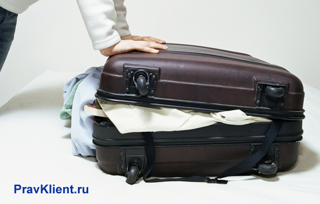Женщина пытается закрыть чемодан